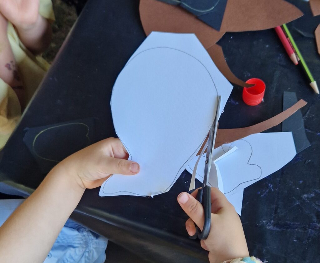 Nahaufnahme von Kinderhänden beim Ausschneiden einer aufgemalten Linie mit Rundung.